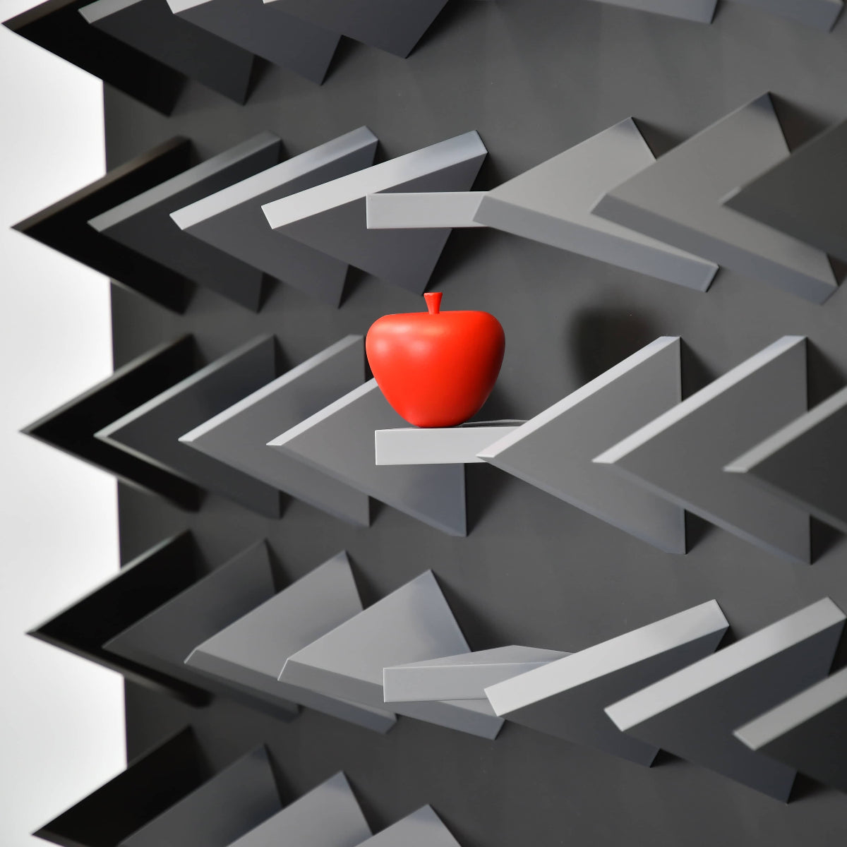 Red apple on a geometric black and gray shelf design