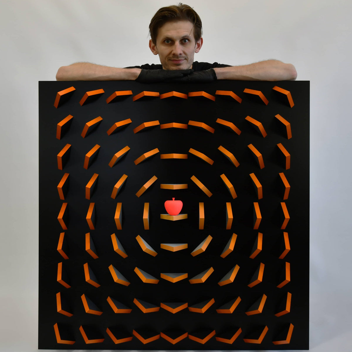 Person holding a large black target with orange arrows and a red heart in the center against a white background